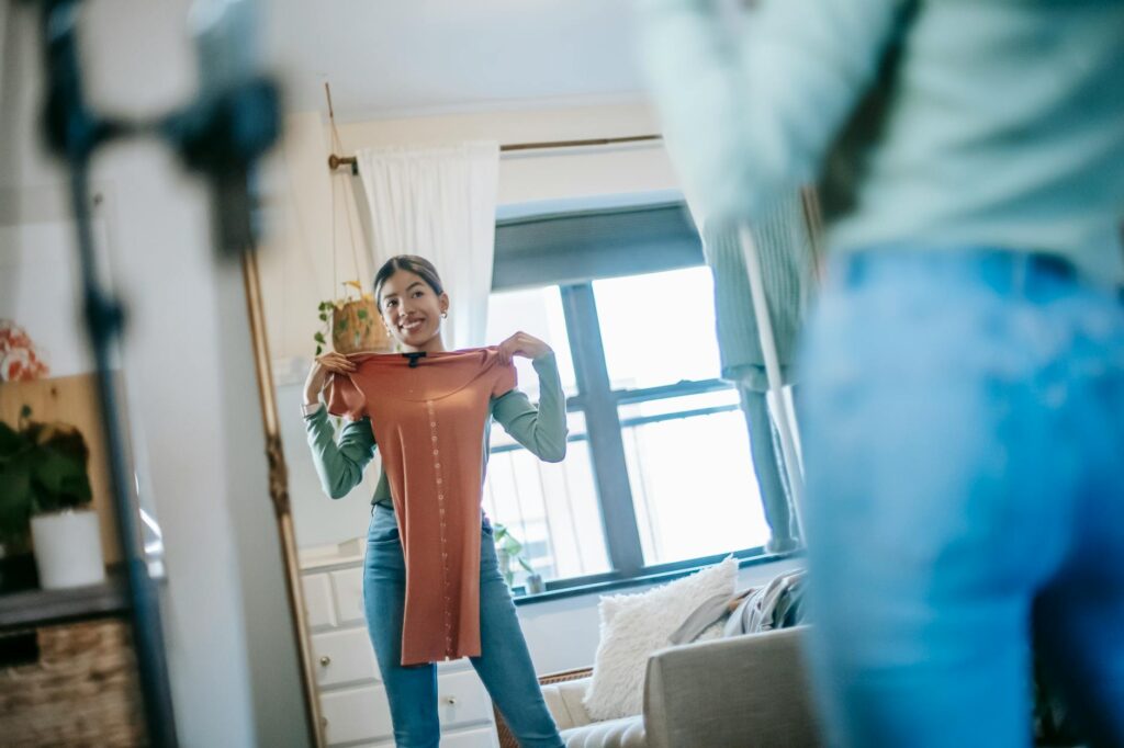 Positive ethnic lady filming vlog on cellphone while demonstrating dress